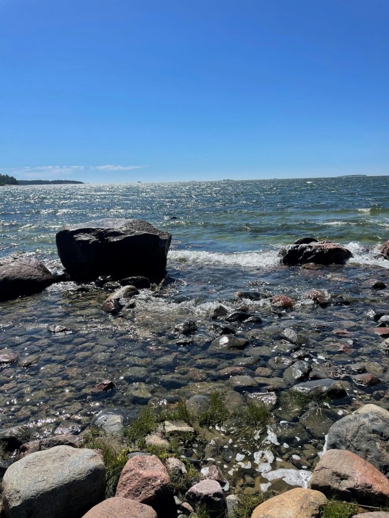 Merenranta, jossa vedestä pilkottaa erikokoisia kiviä.